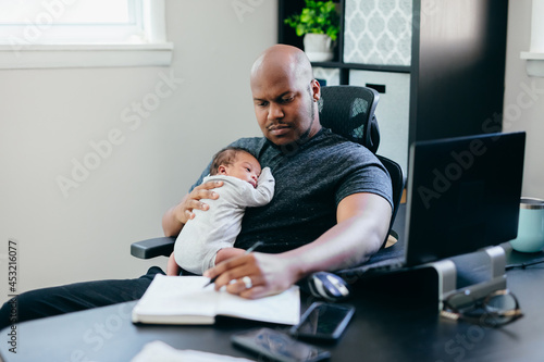 Black dad with newborn working from home photo
