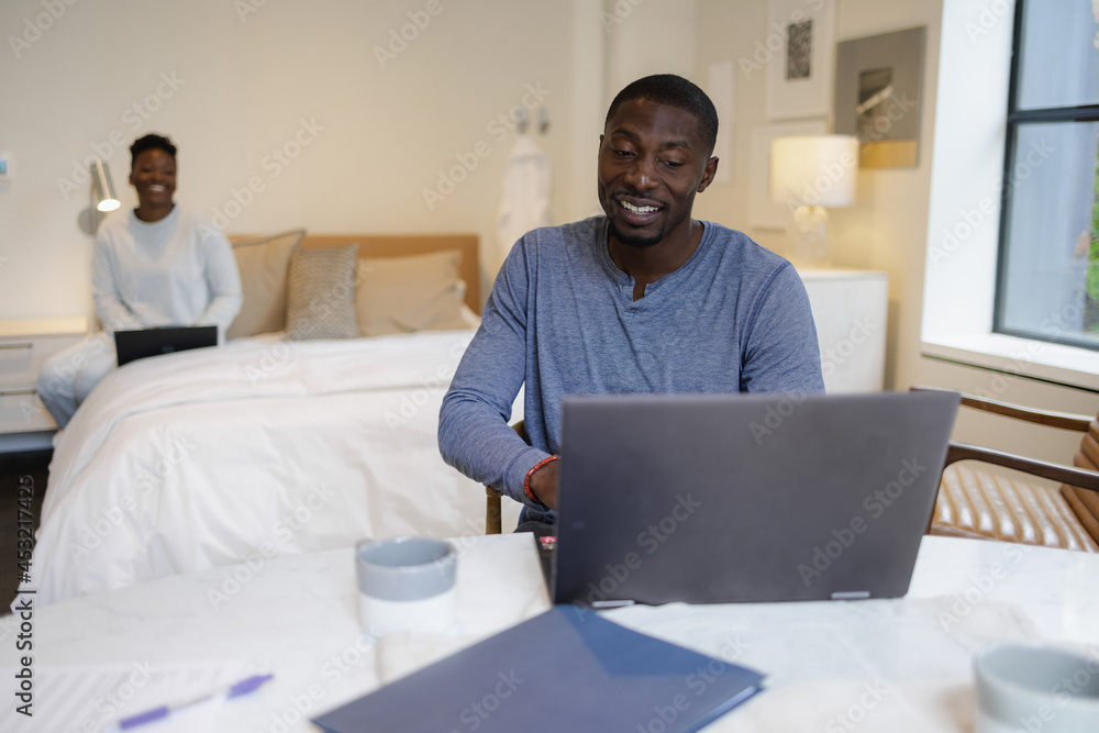Black Couple using laptops in bedroom Black Couple using laptops in bedroom