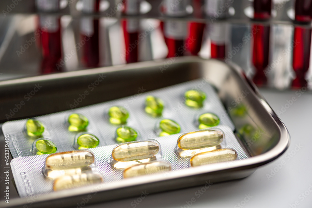 Tray of medicine filled with capsules and medicine strips with test tubes in background on a laboratory table with no people around Tray of medicine filled with capsules and medicine strips with test tubes in background on a laboratory table with no people around
