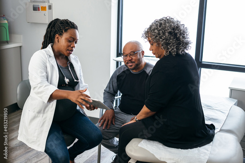 Black pregnant doctor consulting with senior patients 
