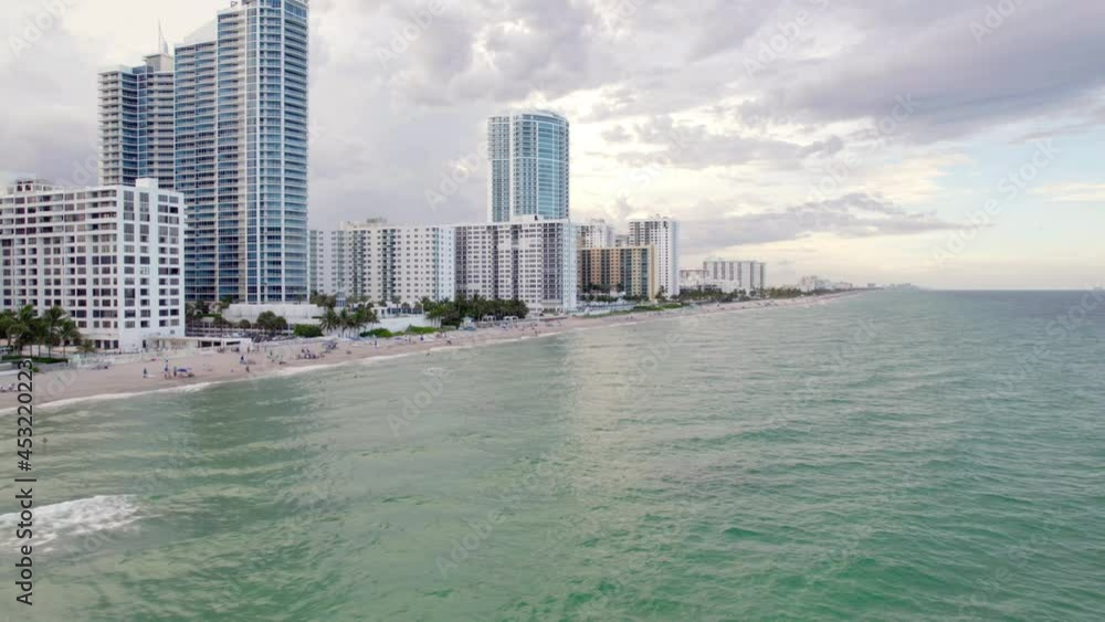 Aerial view of highrise and people at the Sunny isles beach, in cloudy Miami - pan, drone shot Aerial view of highrise and people at the Sunny isles beach, in cloudy Miami - pan, drone shot
