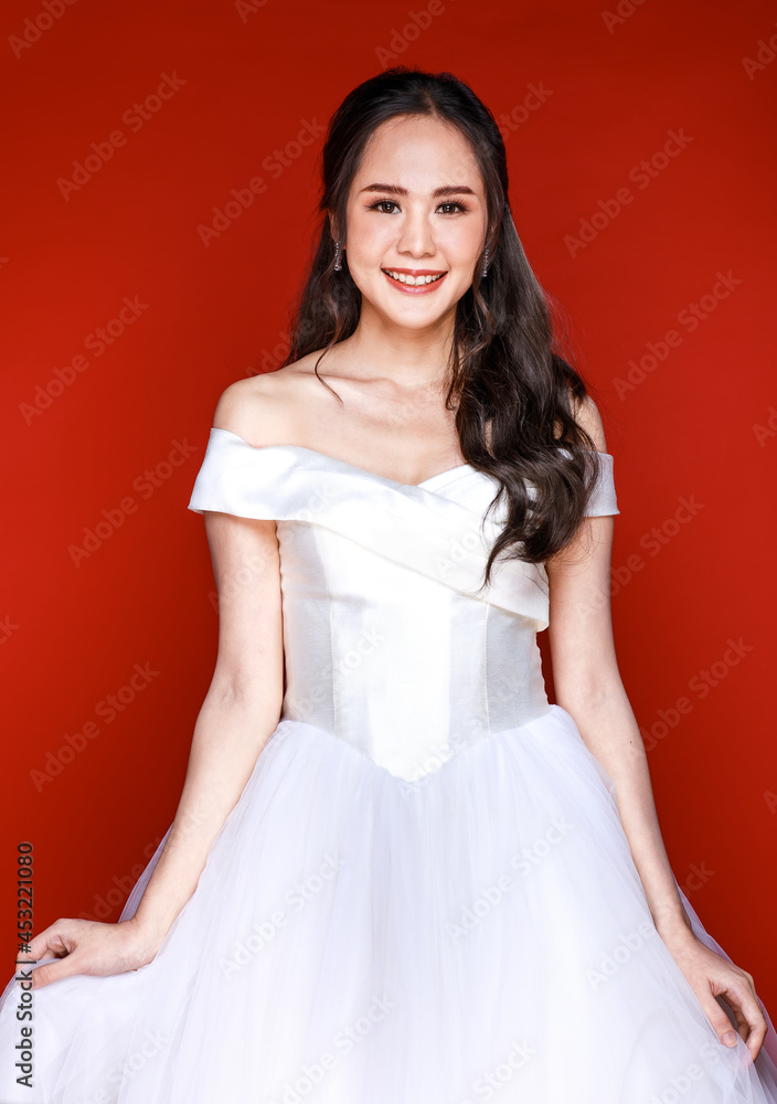 Young attractive Asian woman soon to be bride wearing white wedding gown holding bouquet of flower against red background. Concept for pre wedding photography Young attractive Asian woman soon to be bride wearing white wedding gown holding bouquet of flower against red background. Concept for pre wedding photography
