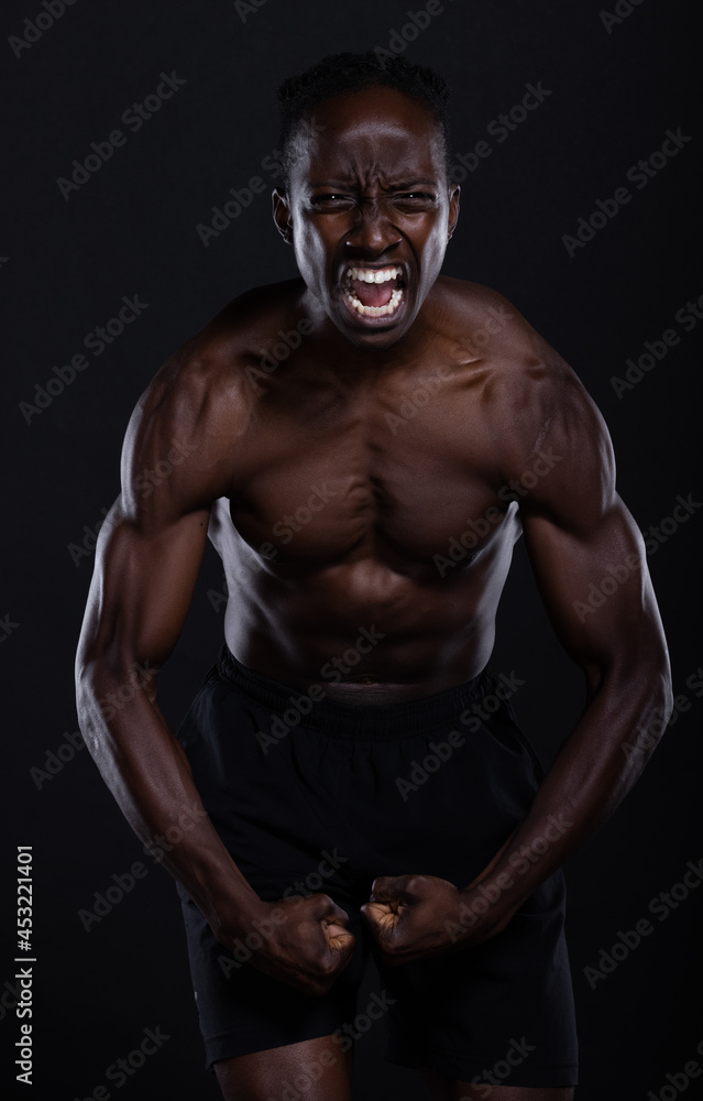 Fit African American man with muscles posing in studio Fit African American man with muscles posing in studio