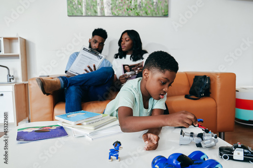 Black Family in clinic waiting room, kid plays with toys