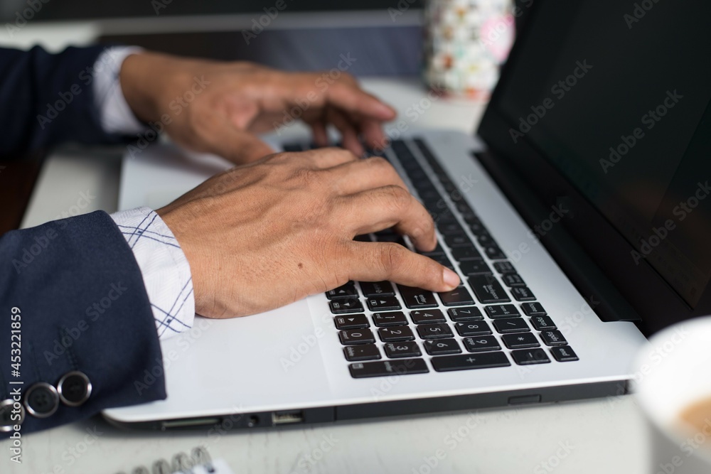 Selective focus shot of closeup hands typing on laptop computer keyboard. Horizontal, copy space for text. 