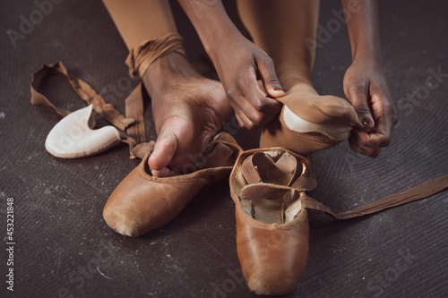 Black ballerina dancer takes off pointe shoes, pushing through pain, perseverance  photo