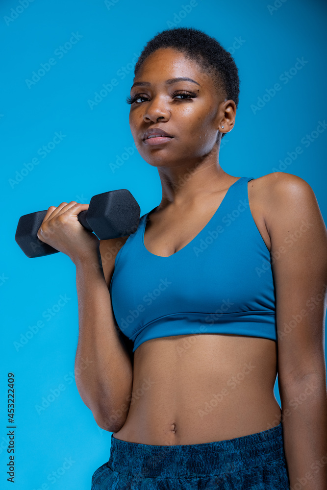 Portrait of pretty African American woman doing dumbbell exercises Portrait of pretty African American woman doing dumbbell exercises