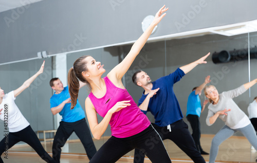 Young smiling woman practicing vigorous lindy hop movements in dance class