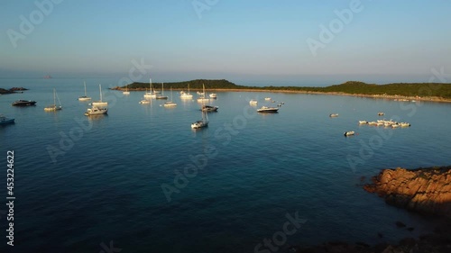 Aerial drone sailing boats on the tourist vacation island Sardinia in Italy by sunset swimming in an idyllic sandy beach bay with clear blue turquoise and calm water close to Isola Tavolara and Olbia.