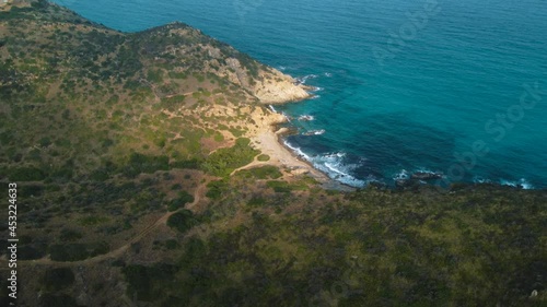 Idyllic Sardinia clear blue turquoise and calm water at a natural sand beach coast bay in Italy with sun and green forest. Aerial drone air flight at a tourist holiday destination on vacation island.