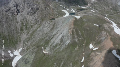 Aerial reveal of thawing snow on high mountain top photo