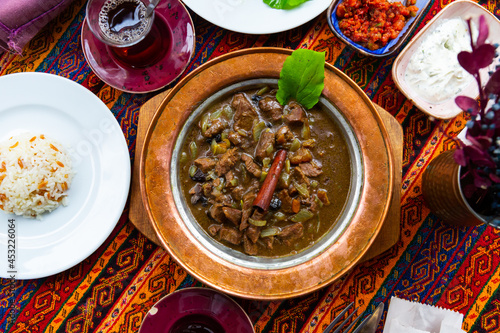 Turkish lamb meat saute mutancana with prunes and rice in traditional ceramic plate photo