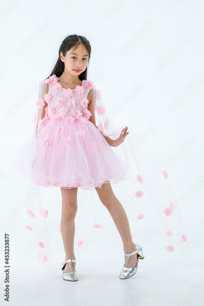 Portrait isolated studio shot of little Asian cute ballerina kid in pink beautiful ballet dress with high heels standing smiling posing elegance gesture in front white background Portrait isolated studio shot of little Asian cute ballerina kid in pink beautiful ballet dress with high heels standing smiling posing elegance gesture in front white background