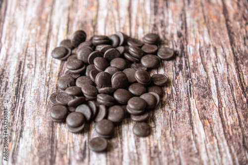 Organic Dark Chocolate Chips on a wooden table. Chocolate morsels on wood background