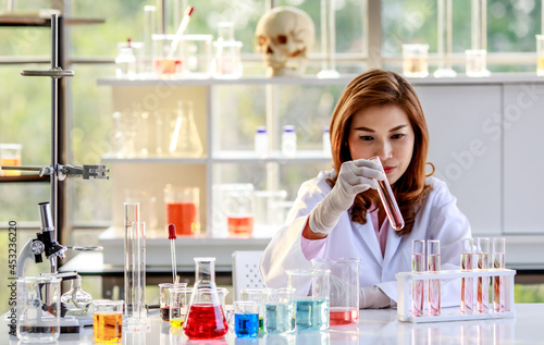Foto Concentrated young Asian female chemistry student conducting experiment and exam