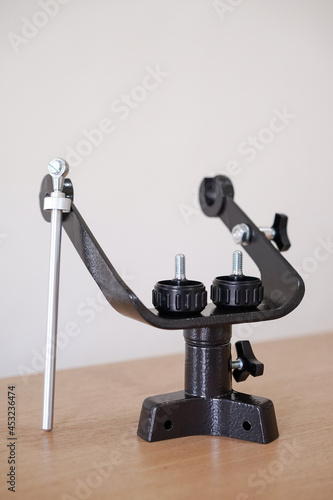 Yoke altazimuth mount, thumb screw, and vertical fine adjustment rod. Telescope parts on wooden table. Astronomy lesson exploring parts of telescope.