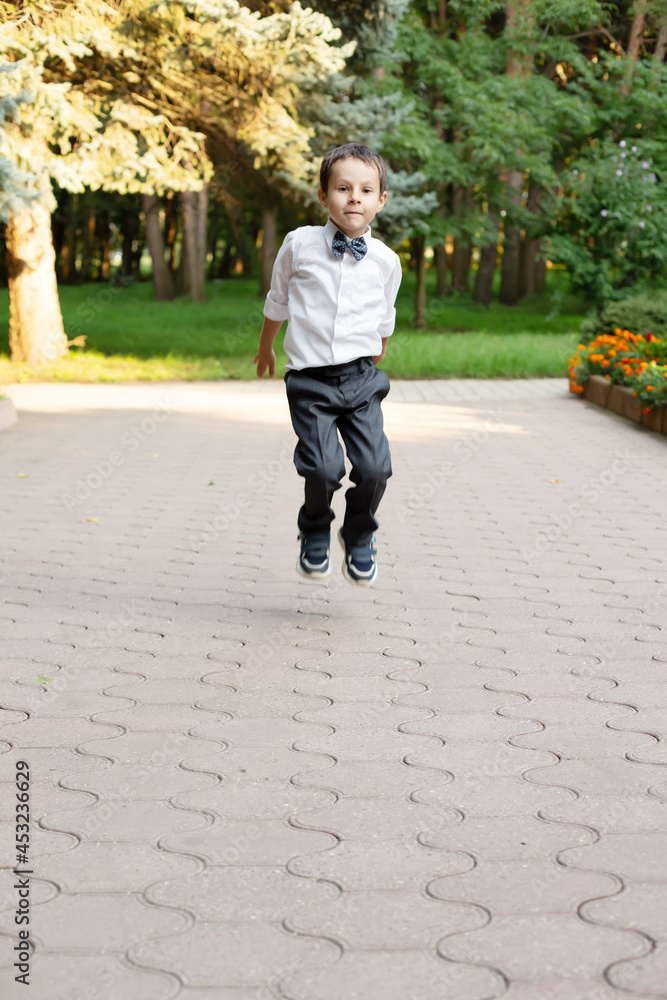 a beautiful little boy a schoolboy a first grader in a white shirt and gray trousers jumps a beautiful little boy a schoolboy a first grader in a white shirt and gray trousers jumps