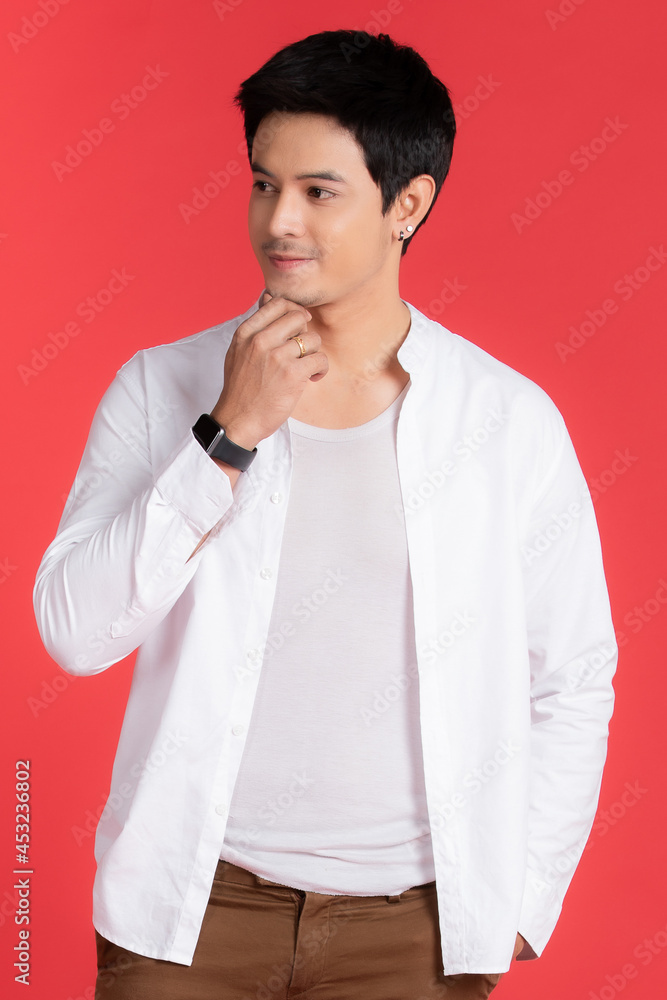 Portrait of handsome Asian man wearing a white shirt Finger poses For a comfortable holiday in an advertising idea isolated on red background. Portrait of handsome Asian man wearing a white shirt Finger poses For a comfortable holiday in an advertising idea isolated on red background.