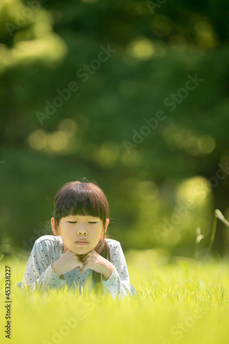 真夏の公園の芝生で遊んでいる可愛い女の子の様子