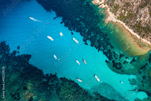 View from above, stunning aerial view of a green and rocky coastline bathed by a turquoise, crystal clear water. Costa Smeralda, Sardinia, Italy.