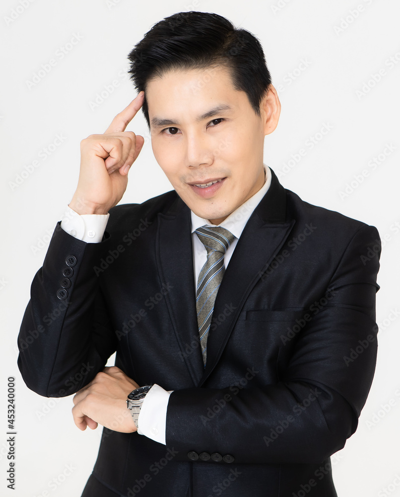 Young and handsome black hair Asian businessman in dark tone suit standing and looking to camera, pose with self-confidence and trust. He touches his forehead with finger in gesture of thinking Young and handsome black hair Asian businessman in dark tone suit standing and looking to camera, pose with self-confidence and trust. He touches his forehead with finger in gesture of thinking