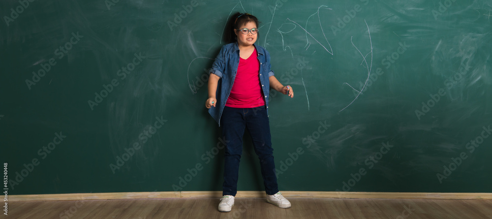 Φωτογραφία Young downs syndrome little Asian girl playing with the cheerful manner in front of green wall in classroom