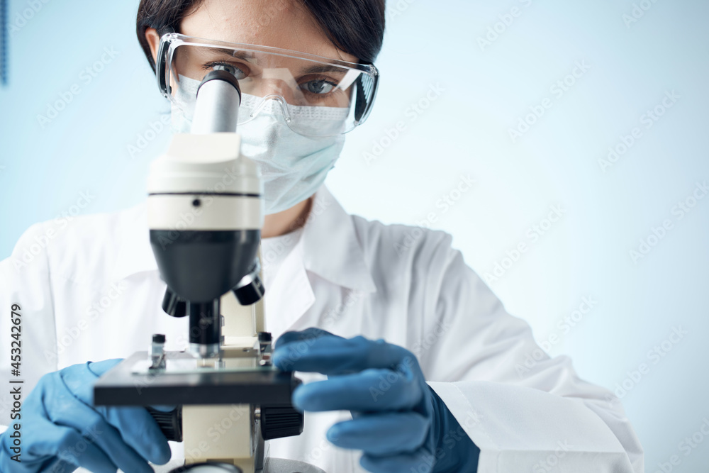 Woman in white coat laboratory science microscope analyzes Woman in white coat laboratory science microscope analyzes