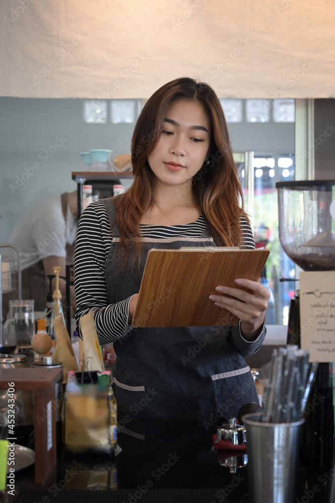 Portrait of young female waitress in apron standing in modern coffee shop. Portrait of young female waitress in apron standing in modern coffee shop.