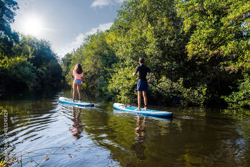 cute young couple paddle boarding on a river photo