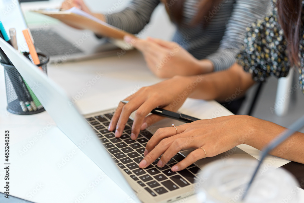 Fototapeta premium Closeup of businesswoman typing on laptop computer next to co-worker