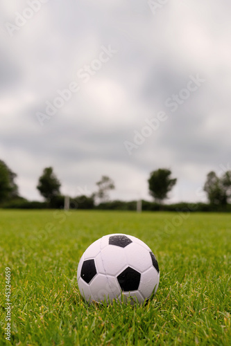 Ball on green grass, Soccer of football goal post in the background.