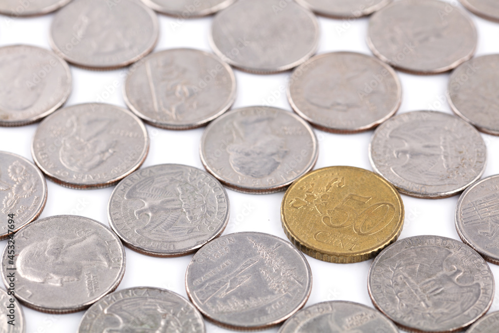 A Euro coin in a spread out dollar coin A Euro coin in a spread out dollar coin