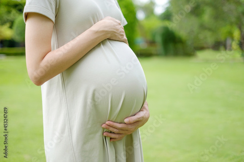 Close-up of pregnant woman in a long dress in pastel colors