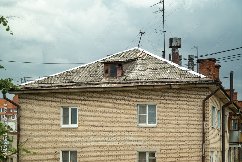 View of the roof of old brick house with chimneys and lots of TV antennas