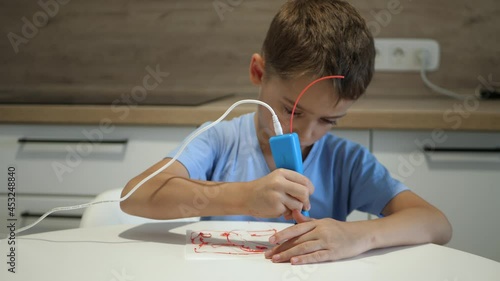 A schoolboy child uses a 3d pen for a 3d drawing. echnologies and children. Business technology. Modern design. Modern design. photo