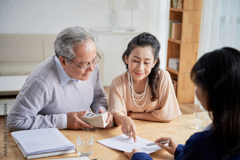 Real estate manager explaining senior couple how to fill sale deed form Real estate manager explaining senior couple how to fill sale deed form