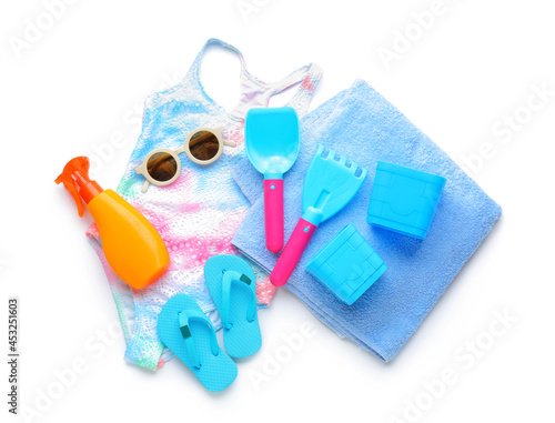 Set of beach accessories for children, stylish swimsuit and bottle of sunscreen on white background