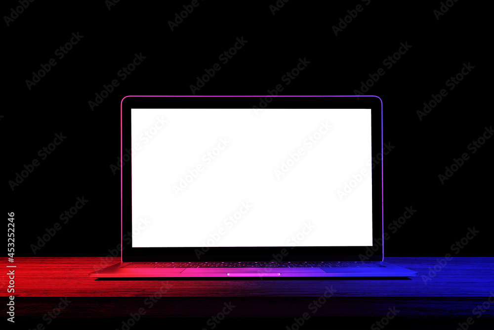 Empty laptop blank screen on wooden top table with red and blue lighting effect in background.