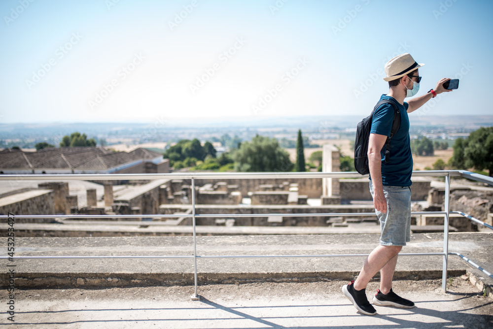 Young tourist man with facial mask taking a selfie in Medina Azahara, Córdoba Young tourist man with facial mask taking a selfie in Medina Azahara, Córdoba