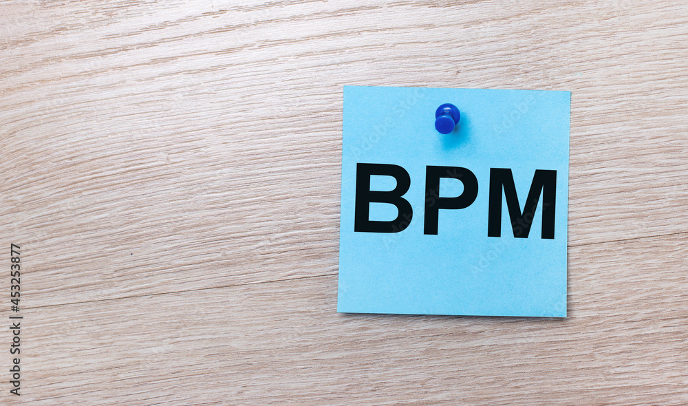 On a light wooden background - a light blue square sticker with the text BPM Business Process Management On a light wooden background - a light blue square sticker with the text BPM Business Process Management
