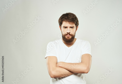 bearded man in a white t-shirt irritated facial expression light background