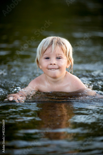 Fototapeta Naklejka Na Ścianę i Meble -  Beautiful portrait of children in lake, kids playing in the water on sunset, summer