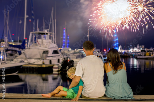 Happy family with child, watching fireworks on a port, sitting and enjoying © Tomsickova