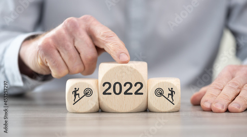Male finger on a wooden cube with concept of business target in 2022