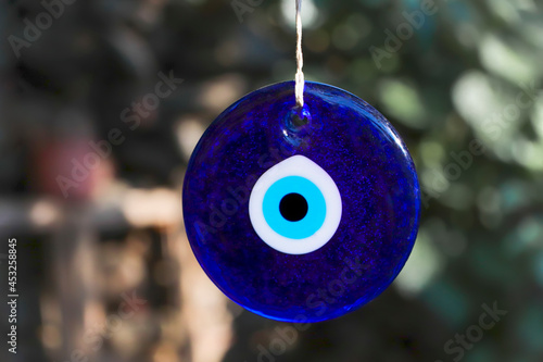 Evil eye bead, Turkiah nazar bead. Blue evil eye beads hanging with a rope from a tree branch. Traditional Evil Eye Amulets. photo