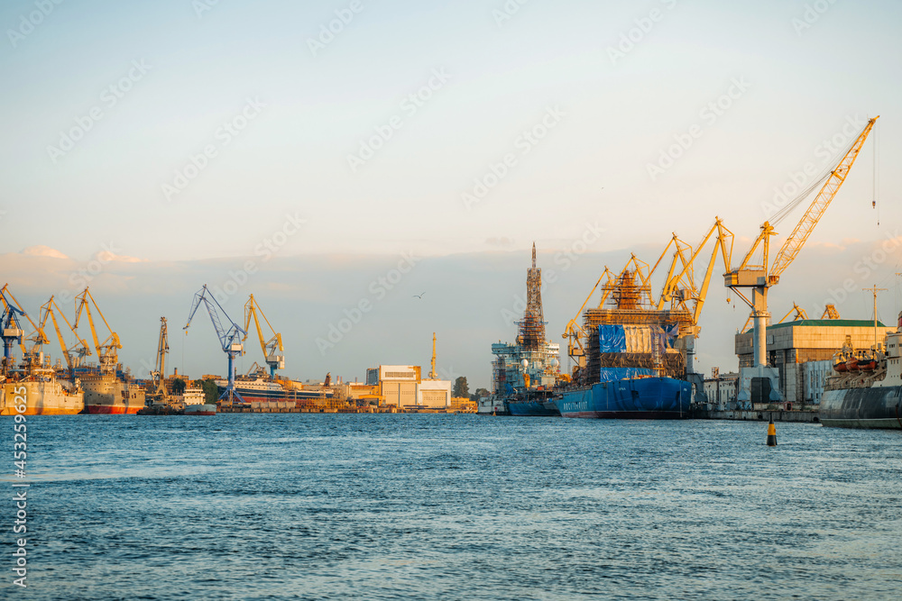 The embankment in the port on Vasilyevsky Island with merchant ships. Saint Petersburg, Russia - 24 June 2021