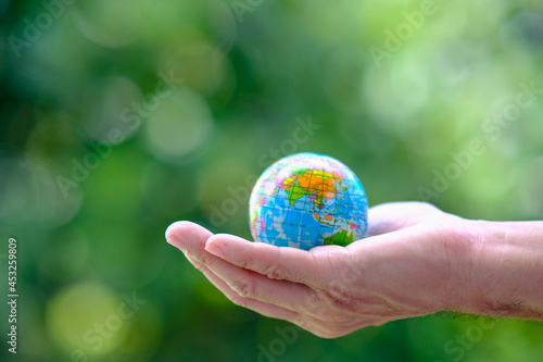 Hand holding globe on green background, ecology, save world
