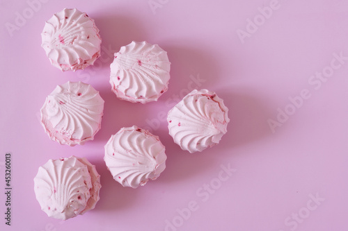 Delicate pink marshmallow lies on a pink background. View from above. Free space for an inscription. Natural lighting in the kitchen