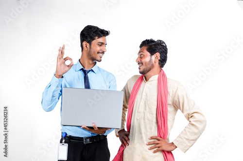 Indian bank officer or corporate government employee showing some information to farmer in laptop.