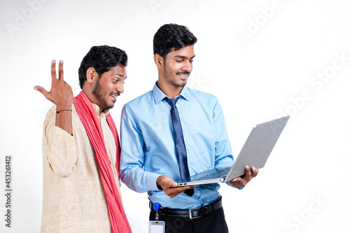 Indian bank officer or corporate government employee showing some information to farmer in laptop. photo